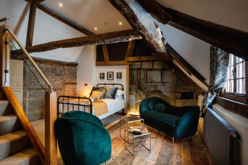 um quarto com uma cama e 2 cadeiras verdes em Old Infirmary em Worcester