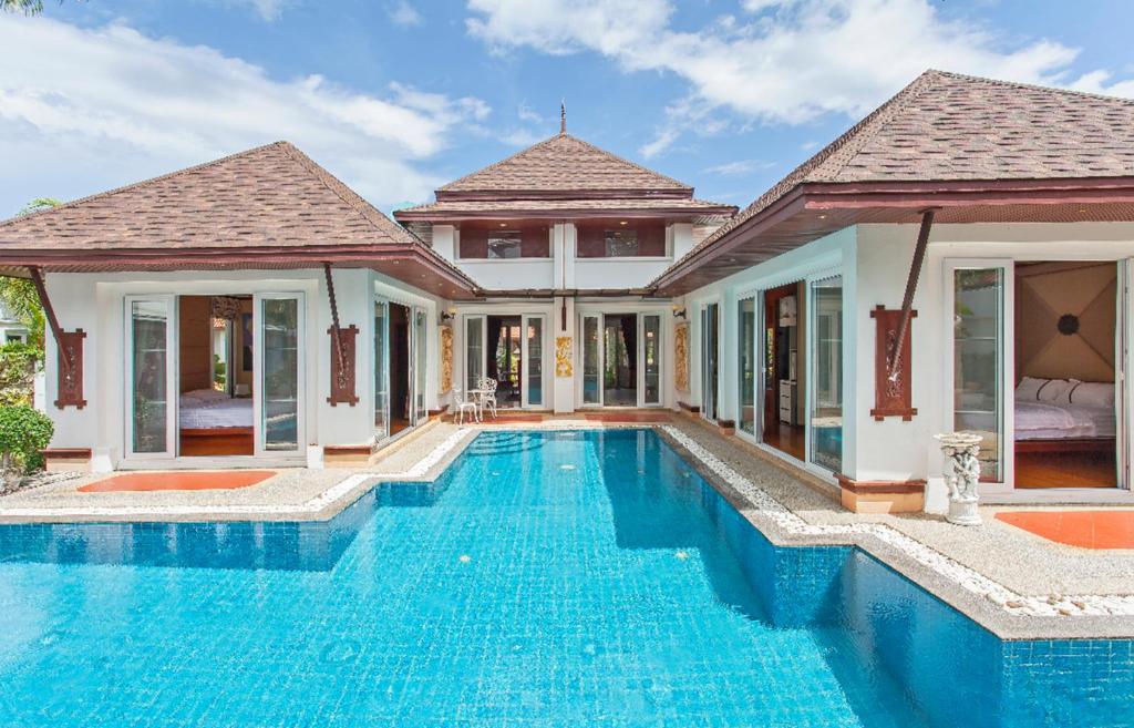 a villa with a swimming pool in front of a house at Thai style villa with very beautiful private pool in Kamala Beach