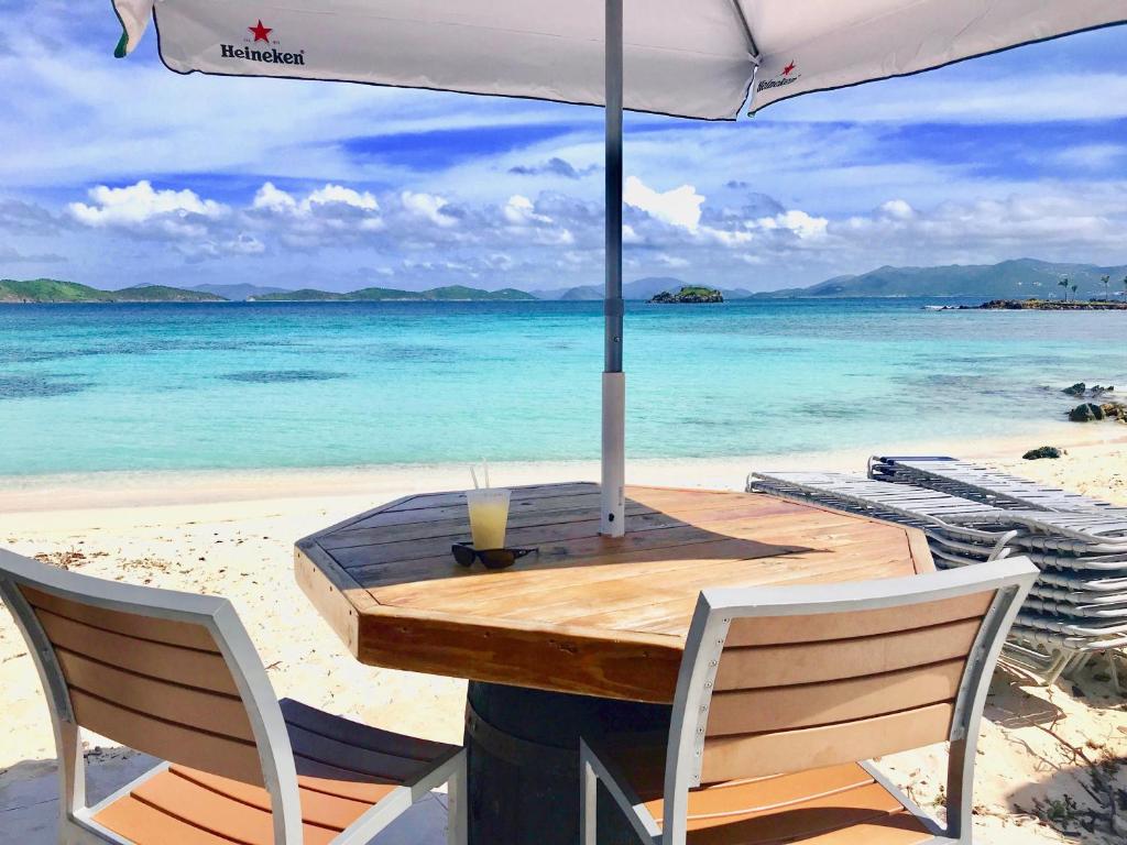 a wooden table on the beach with an umbrella at Ocean Front Sapphire del Mar B-107 in St Thomas