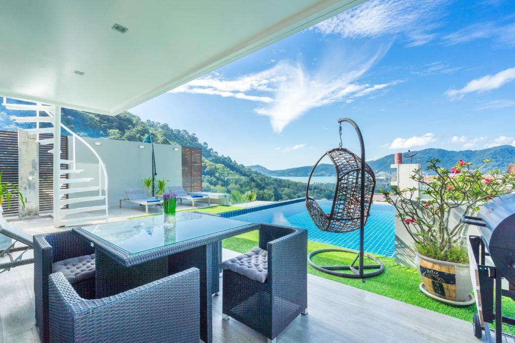 un patio con tavolo, sedie e piscina di Sirirat Sea-view Villa a Patong Beach
