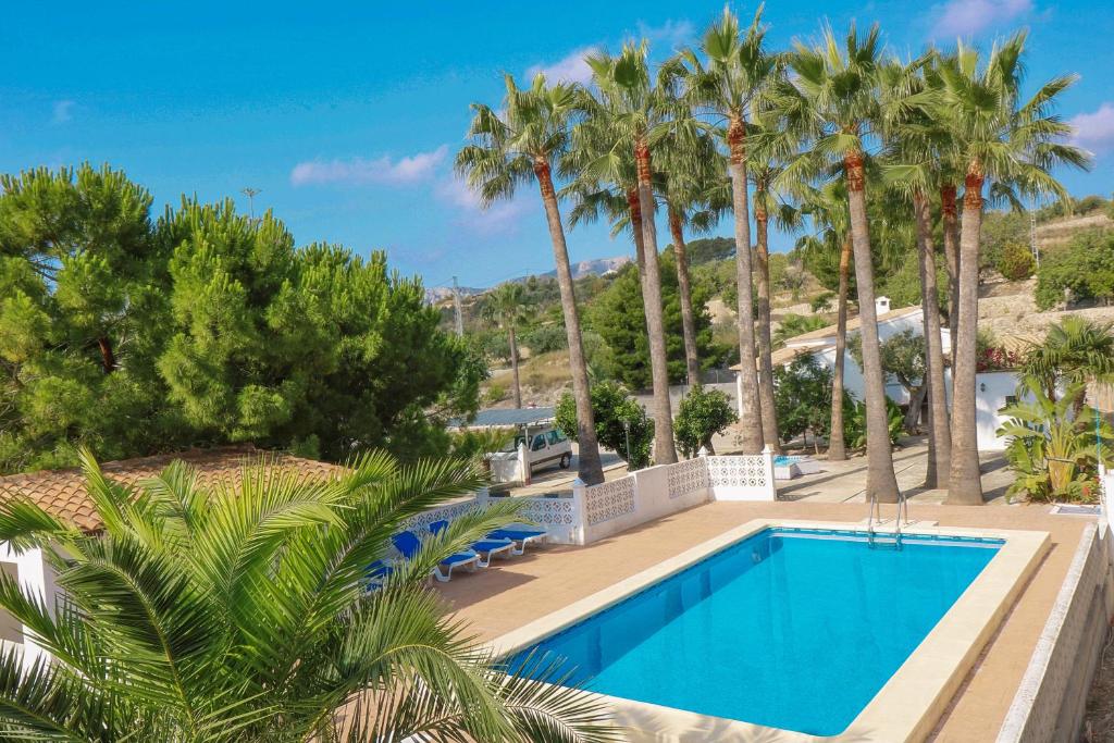 una piscina en un complejo con palmeras en Finca Alhambra - spacious and characterful property in Benissa en Benissa