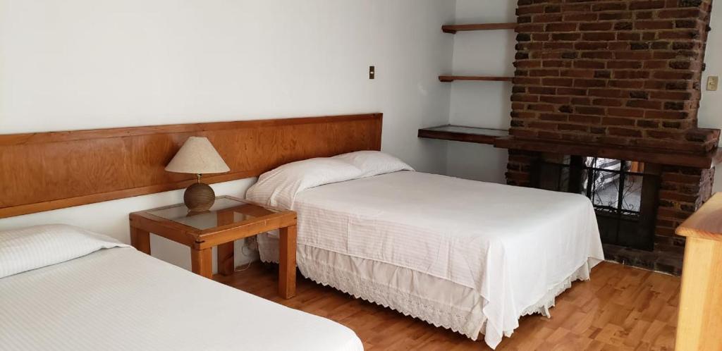 a bedroom with two beds and a table with a lamp at Anys Hostal in Mexico City