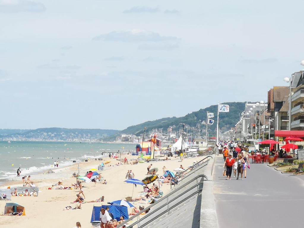 une plage avec beaucoup de monde et l'océan dans l'établissement 2 pièces Front de Mer ensoleillé et calme accès direct plage, à Cabourg