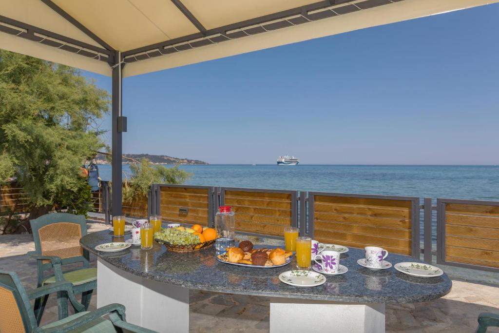 - une table avec de la nourriture sur une terrasse donnant sur l'océan dans l'établissement Venetico Beachfront Apartments & Suites - 2 Bedroom Apartment, à Argassi