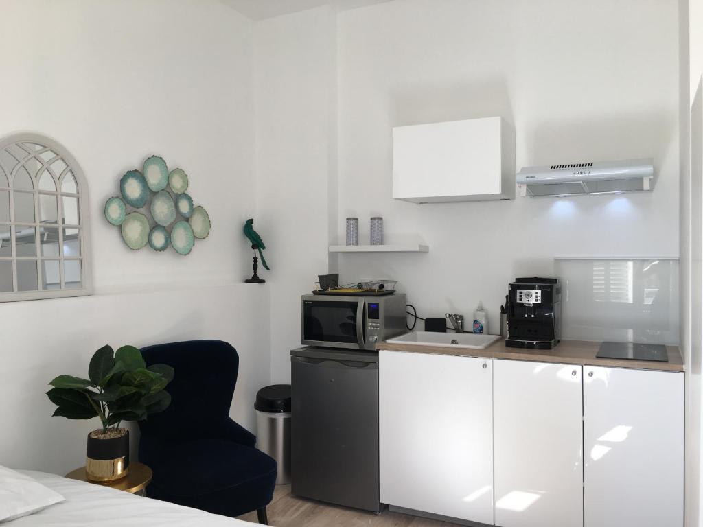 a kitchen with a microwave and a chair in a room at Le Bahia centre la Brèche wifi linge de pressing in Niort