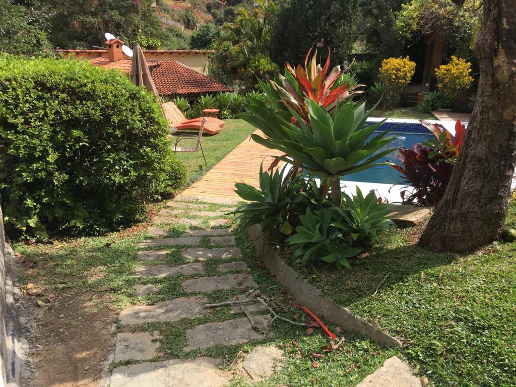 un jardín con una pasarela de madera junto a una piscina en CASA RANXOXITA en Itaipava