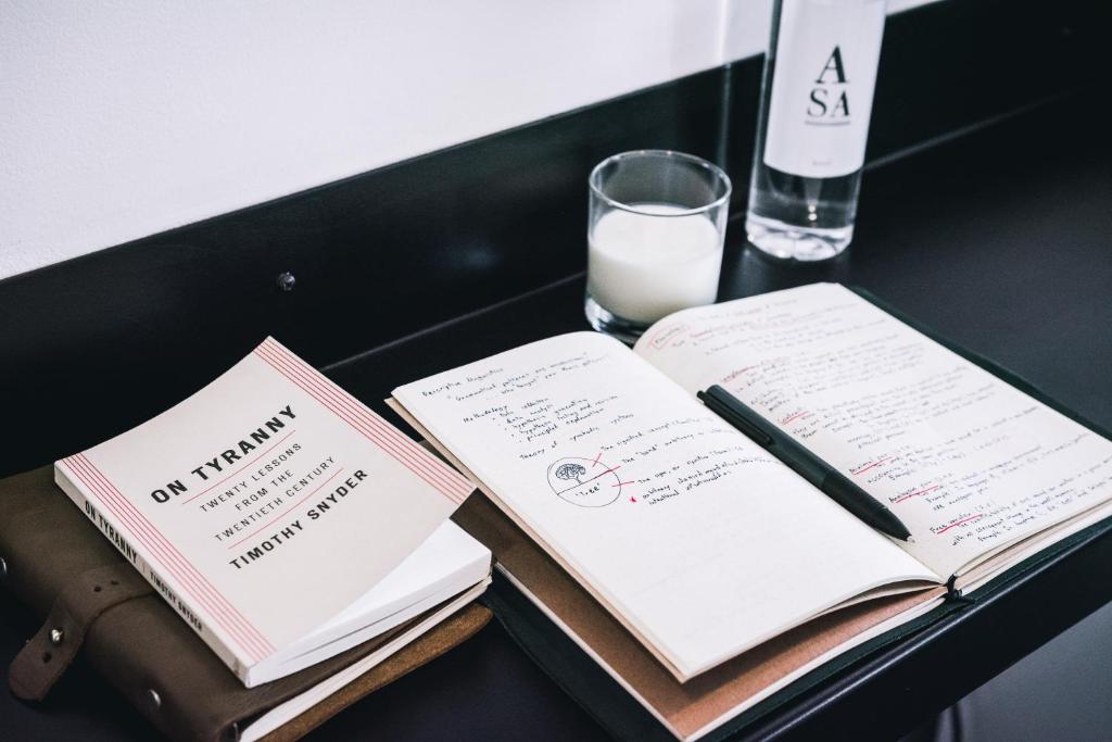 A small table is styled with books, a notebook, a pen, and milk.