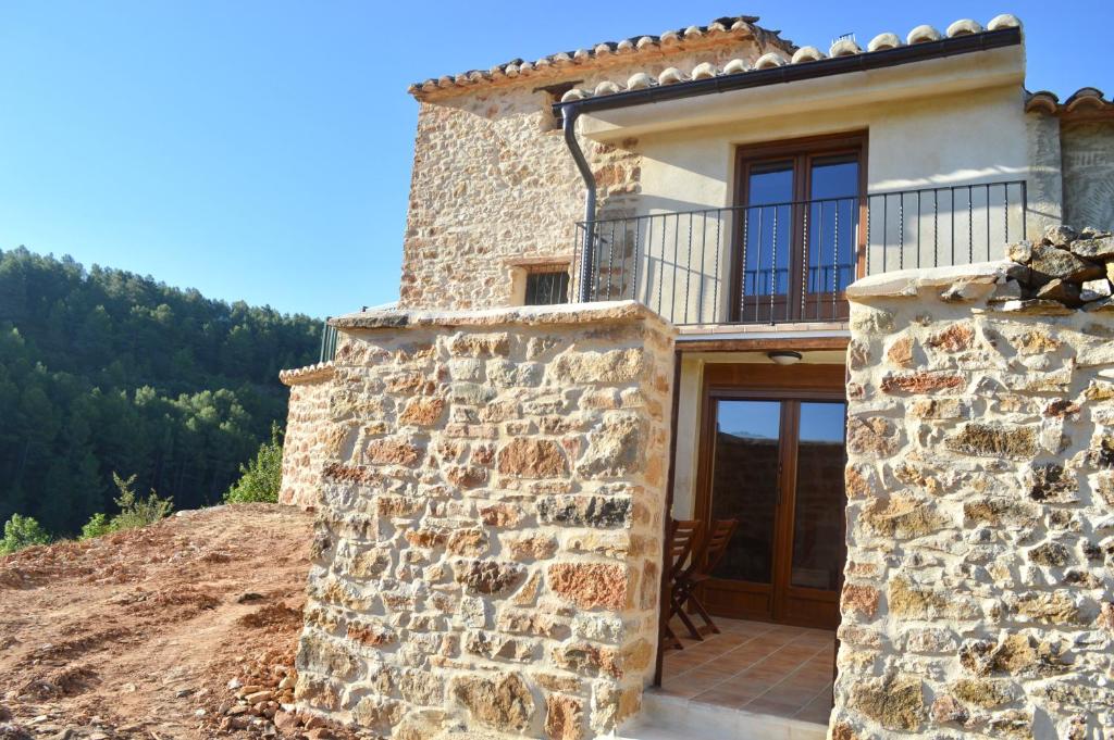 uma casa de pedra com uma varanda numa colina em Casa Cerrito em Cortes de Arenoso