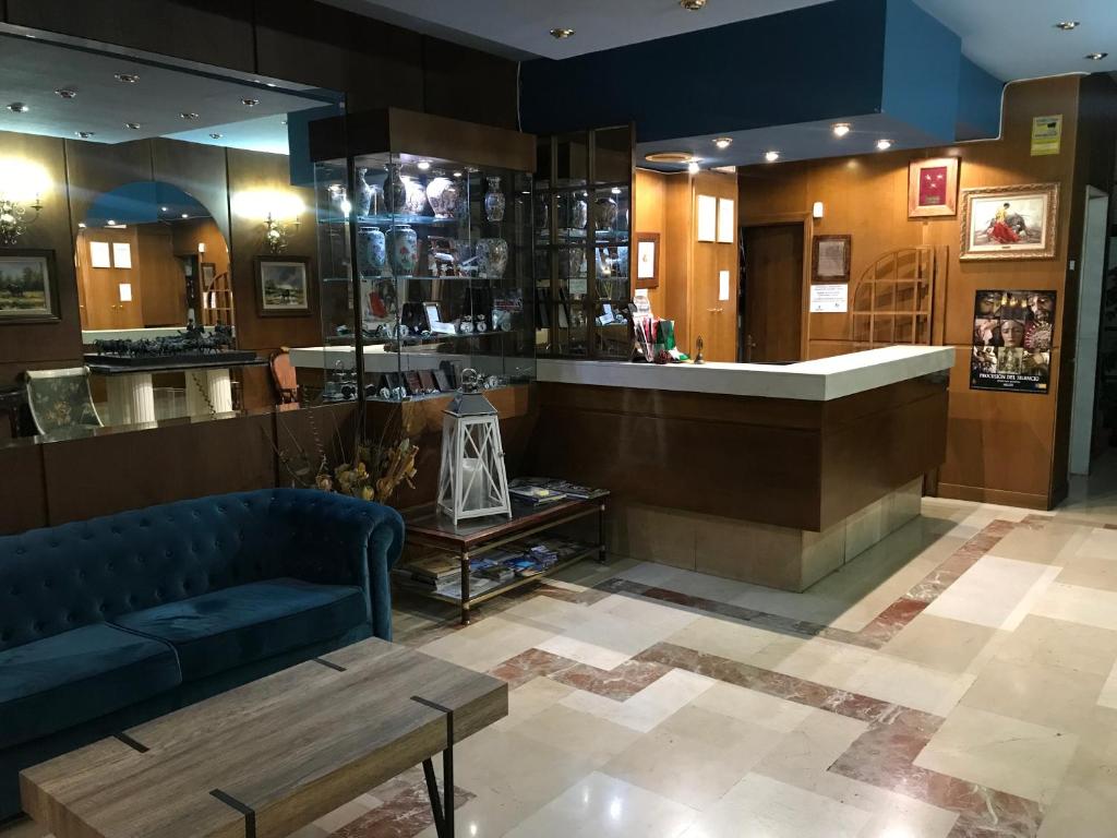 a lobby with a blue couch and a counter at Hotel Reina Victoria in Hellín