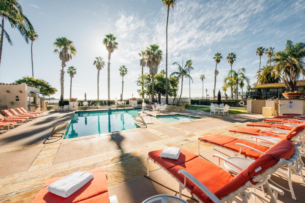 
a beach with a pool, chairs, tables and umbrellas at Harbor View Inn in Santa Barbara

