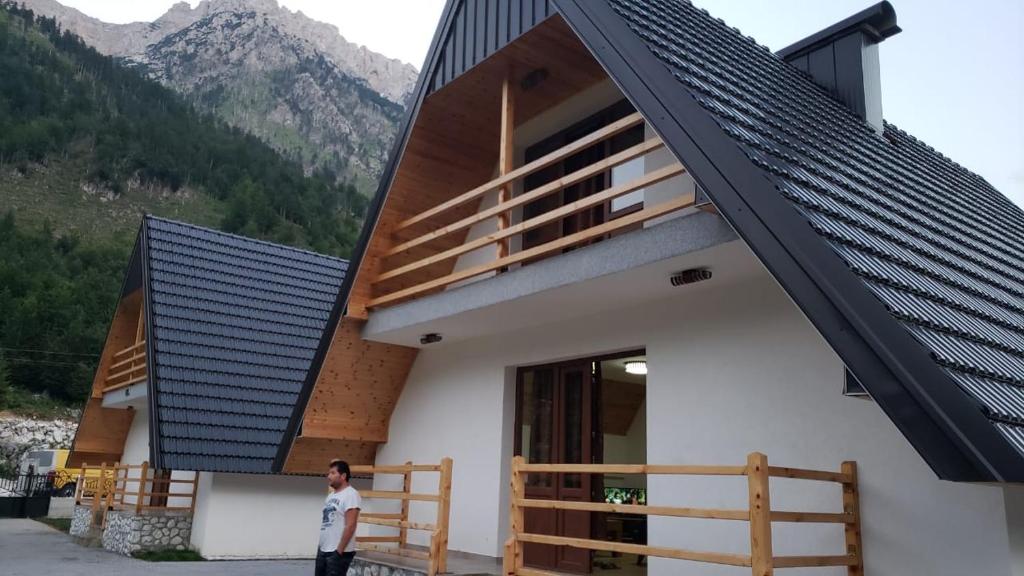 un homme debout devant une maison avec toit dans l'établissement Bujtinat e lugines Valbone, à Valbonë