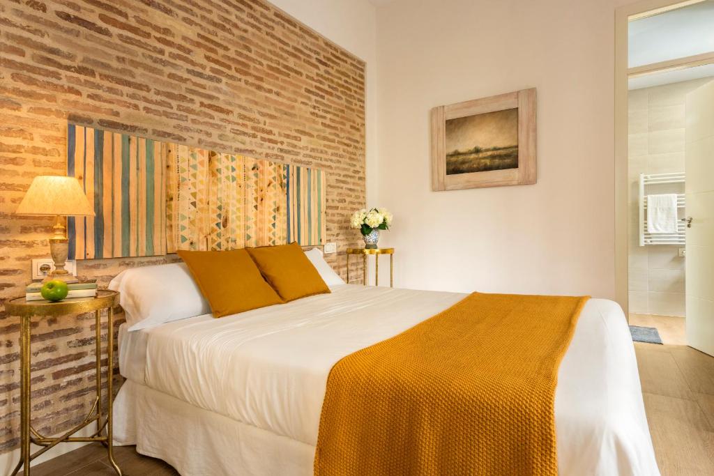 - une chambre avec un lit et un mur en briques dans l'établissement Misterhost Triana Patio de las Flores, à Séville