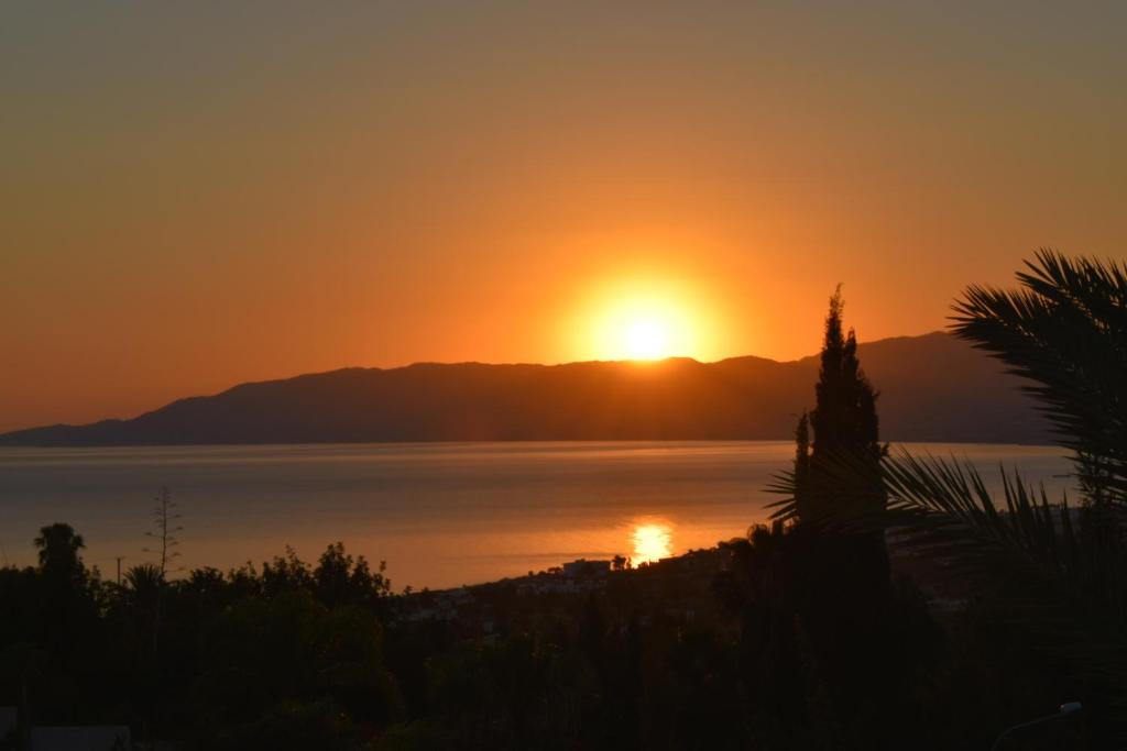 einen Sonnenuntergang über dem Wasser mit Bergen im Hintergrund in der Unterkunft Villamia in Neo Chorio