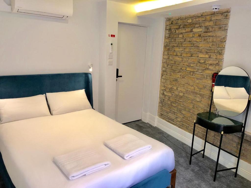 a bedroom with a bed and a chair and a brick wall at Widegate Residential in London