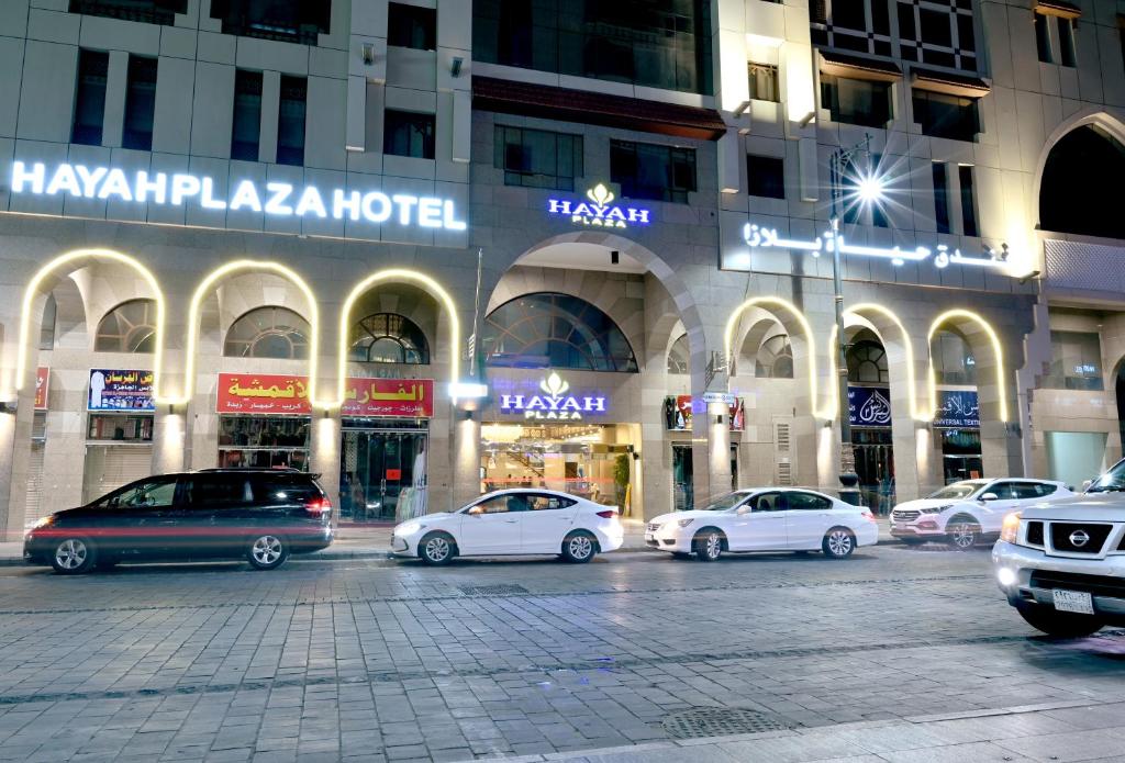 un grupo de coches estacionados frente a un edificio en Hayah Plaza Hotel en Medina