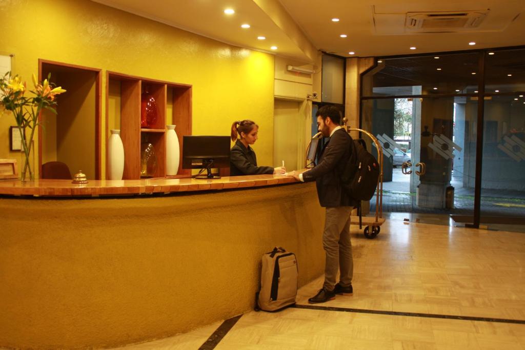 a man and a woman standing at a reception counter at Gala Hotel in Viña del Mar