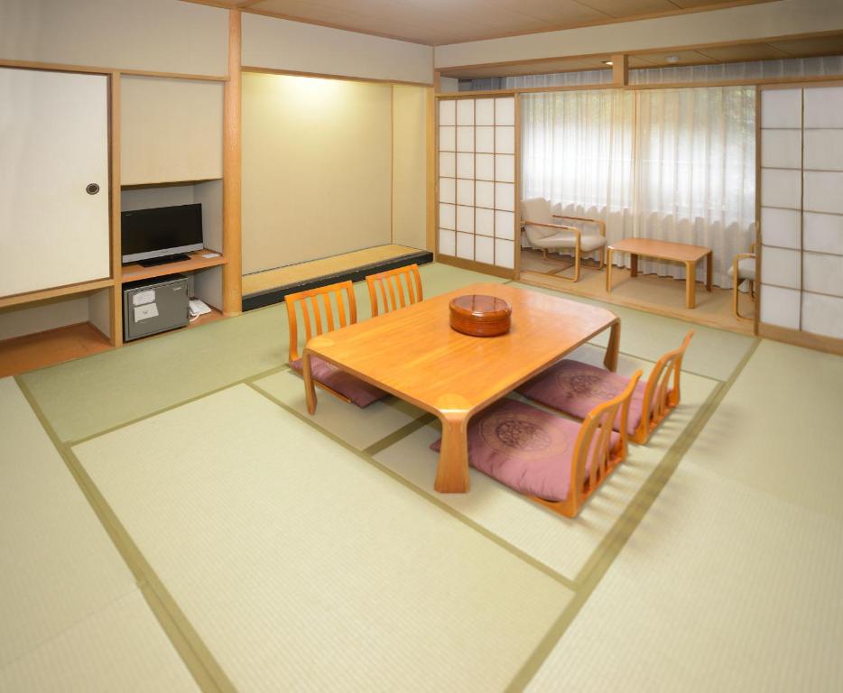 a living room with a wooden table and chairs at Miyajima Morinoyado in Miyajima