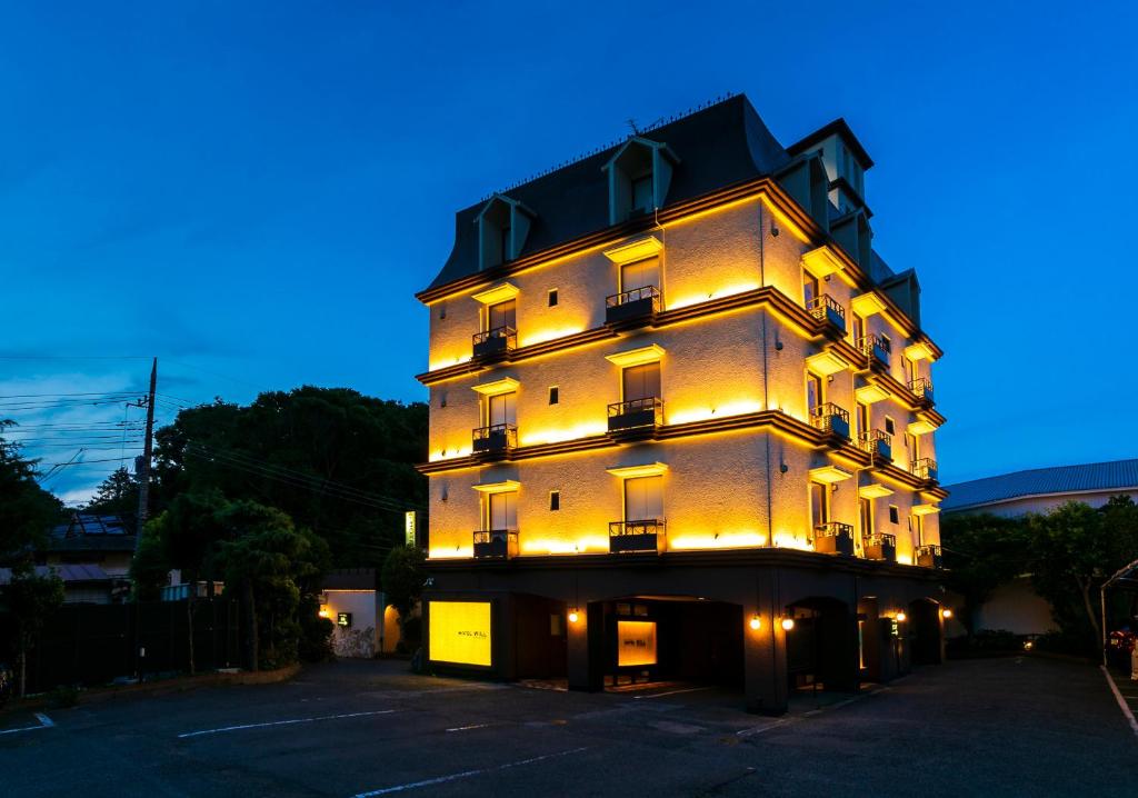 um edifício alto com luzes acesas à noite em Hotel WILL Kashiwa (Adult Only) em Kashiwa