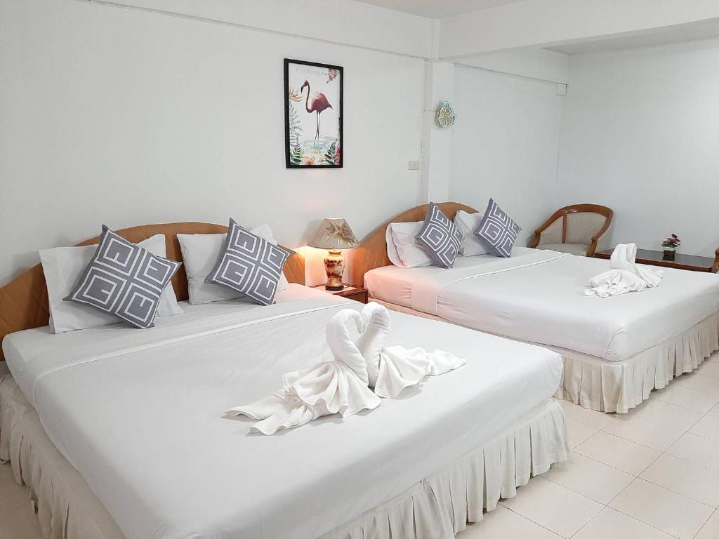 two beds in a room with white walls at สตาร์ รีสอร์ท (สี่แยก จปร) in Nakhon Nayok