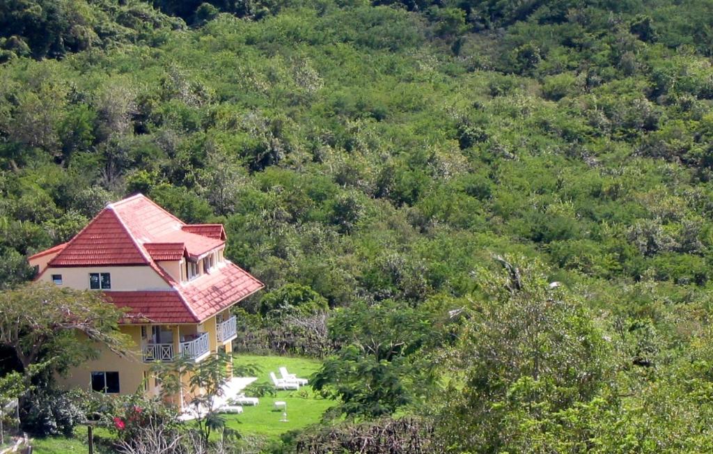 une maison avec un toit rouge au sommet d'une colline dans l'établissement Domaine de l'Anse Ramier, à Les Trois-Îlets