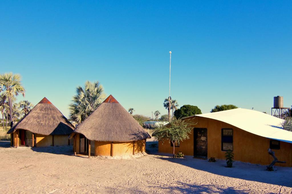 un groupe de maisons au toit de chaume dans le désert dans l'établissement Ongula Village Homestead Lodge, à Omupumba