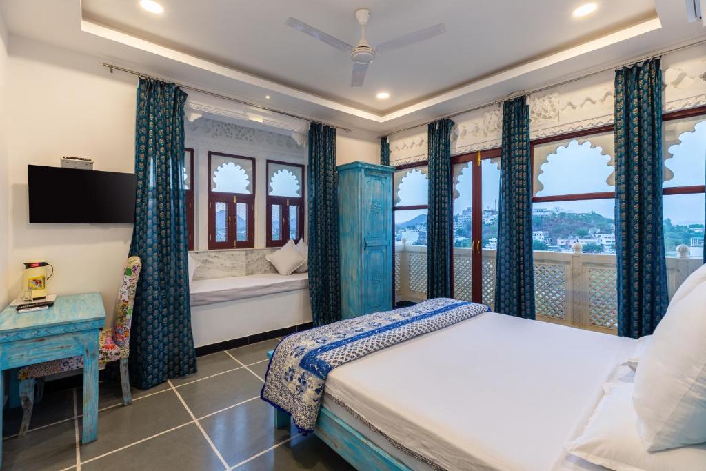 a bedroom with a bed and windows and a tv at Hotel Mewari Villa in Udaipur