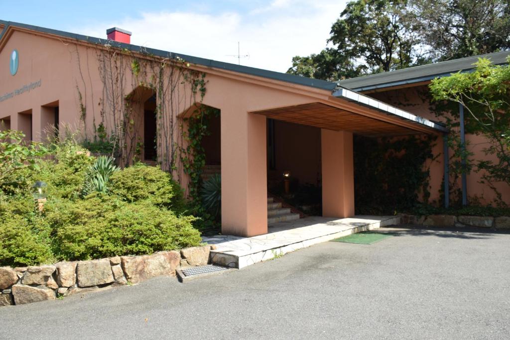 ein rosafarbenes Gebäude mit einer Veranda und einigen Büschen in der Unterkunft Taiyou no Ouchi in Tonosho