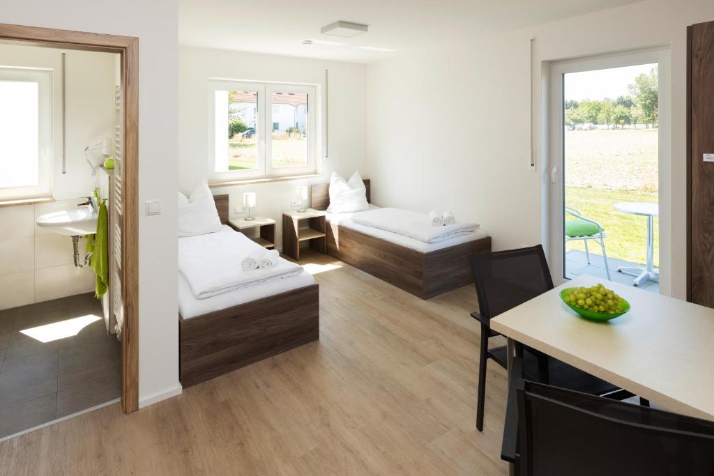 a room with two beds and a table and a mirror at Green Guest House in Wörth an der Isar