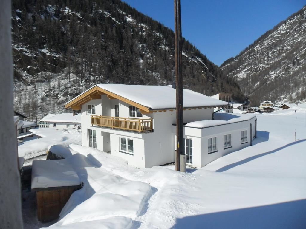 une maison recouverte de neige devant une montagne dans l'établissement Apart Florian, à Sölden