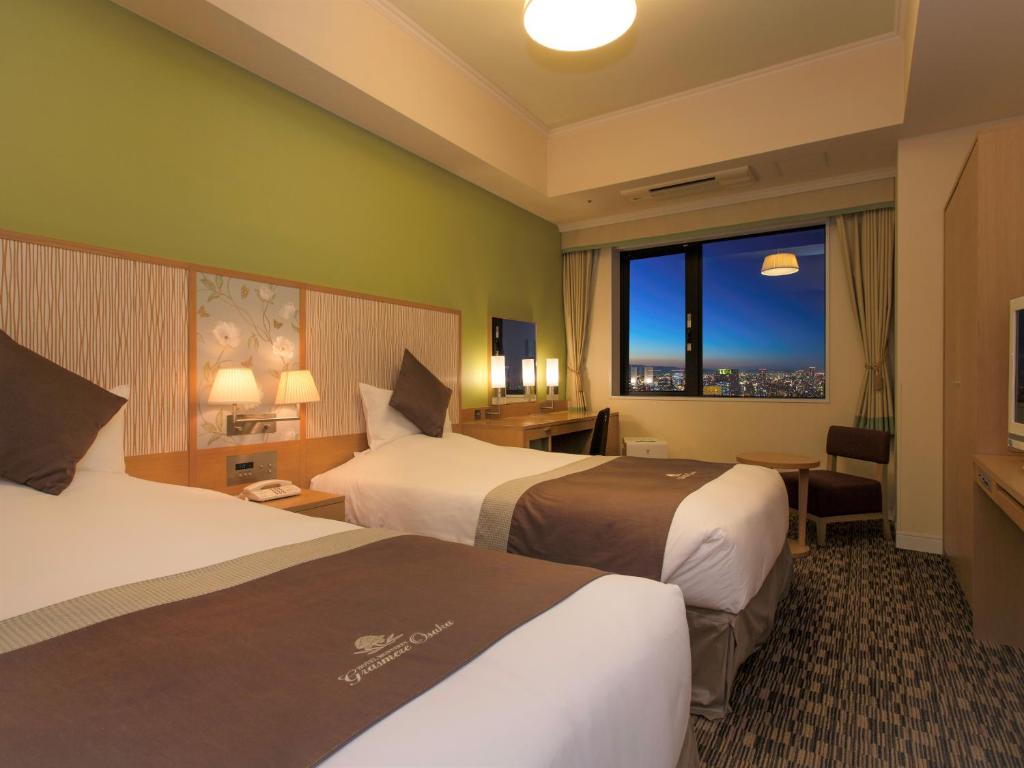 a hotel room with two beds and a window at Hotel Monterey Grasmere Osaka in Osaka
