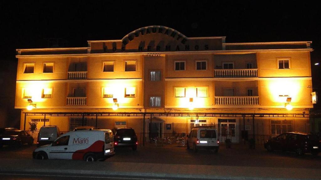 un edificio con coches aparcados delante de él por la noche en Hostal Los Hermanos, en Baza