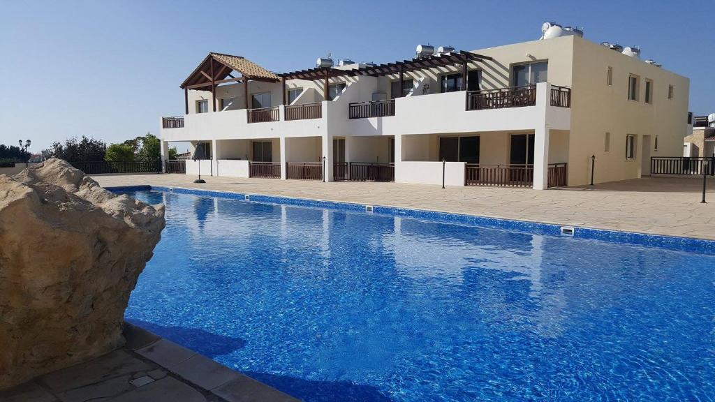 a villa with a swimming pool in front of a building at Studio, E104 with double bed, kitchen & shower room, sunny balcony in Peyia