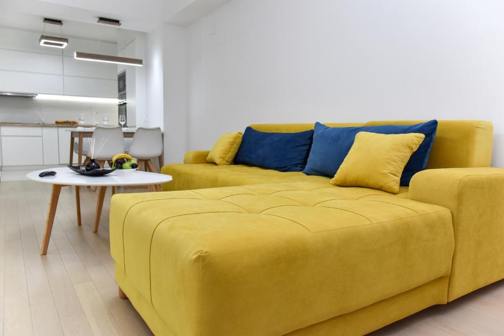 a yellow couch in a living room with a table at Lux Apartment Flatiron Skopje in Skopje