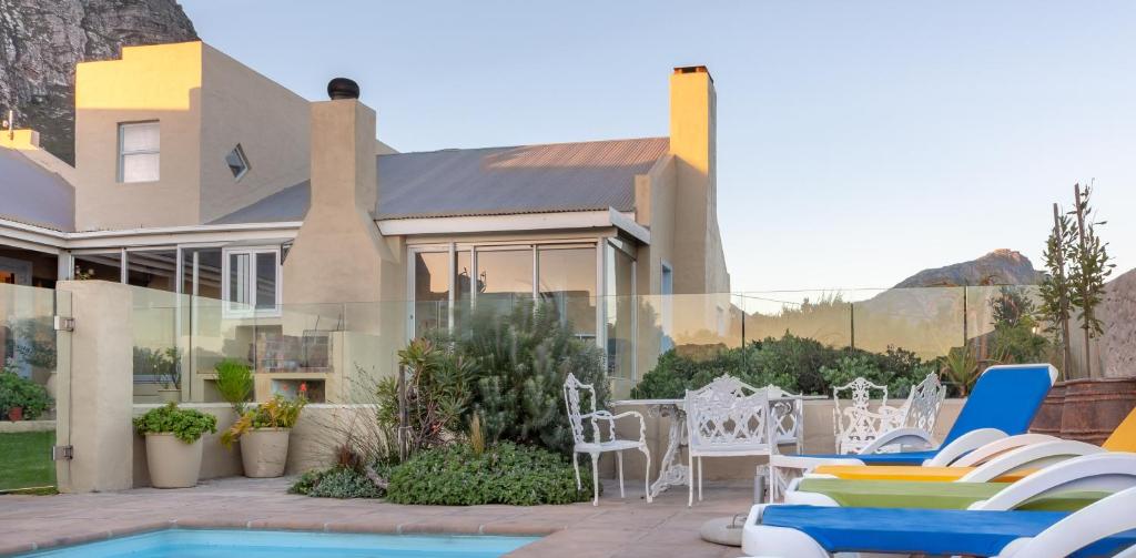 een huis met een patio met stoelen en een zwembad bij Fijnbos Manor in Bettyʼs Bay