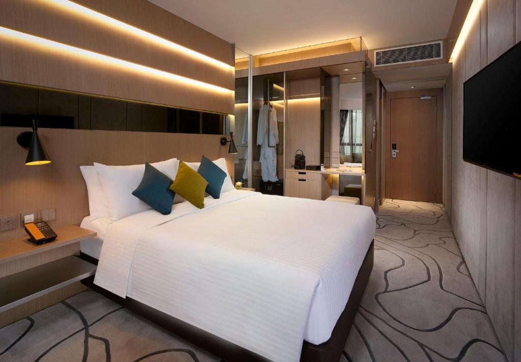 una camera da letto con un grande letto bianco e una televisione di The Harbourview - Chinese YMCA of Hong Kong a Hong Kong