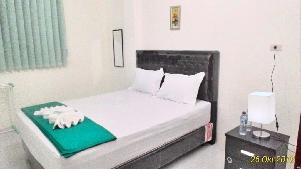 um pequeno quarto com uma cama com uma almofada verde e uma cama sidx sidx sidx em Balige J&J Guest House 2 em Balige