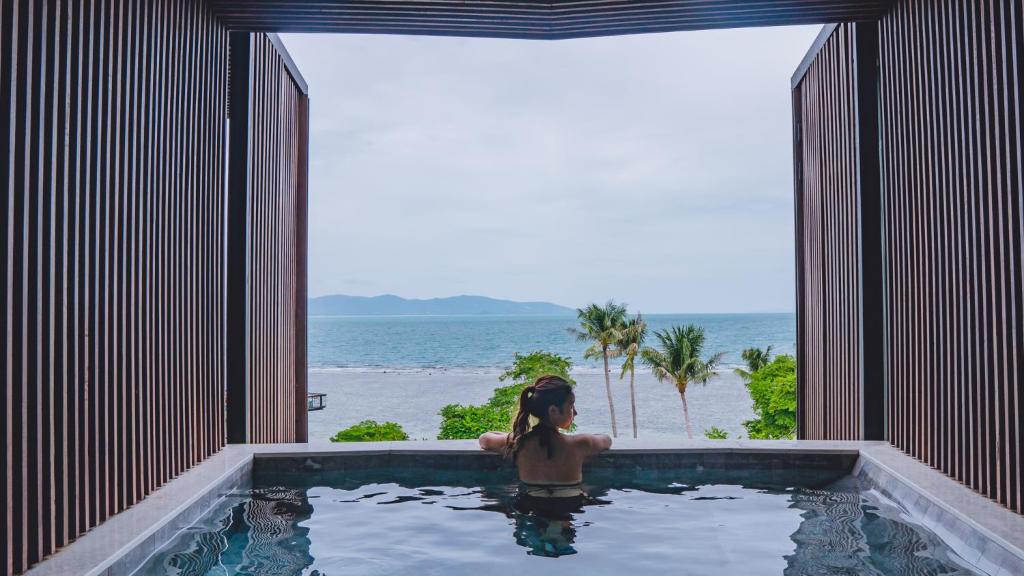 a woman in a swimming pool looking out at the ocean at The Cabin Beach Resort in Haad Rin