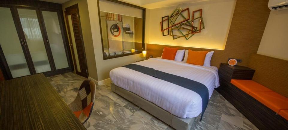 ein Schlafzimmer mit einem großen weißen Bett mit orangefarbenen Kissen in der Unterkunft Dragon River Avenue in Phitsanulok