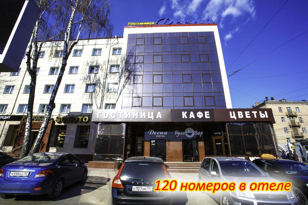 twee auto's geparkeerd voor een gebouw bij Hotel Desna in Bryansk