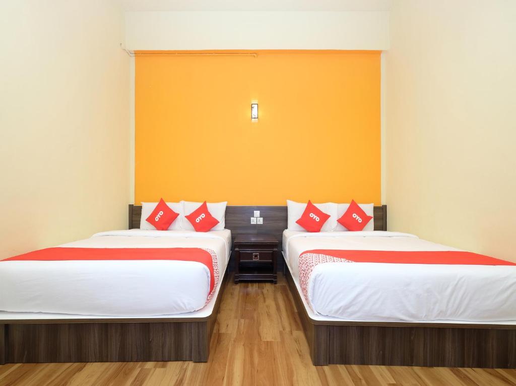 2 Betten in einem Zimmer mit roten und weißen Kissen in der Unterkunft OYO 44029 Tudor Home Inn in Cameron Highlands