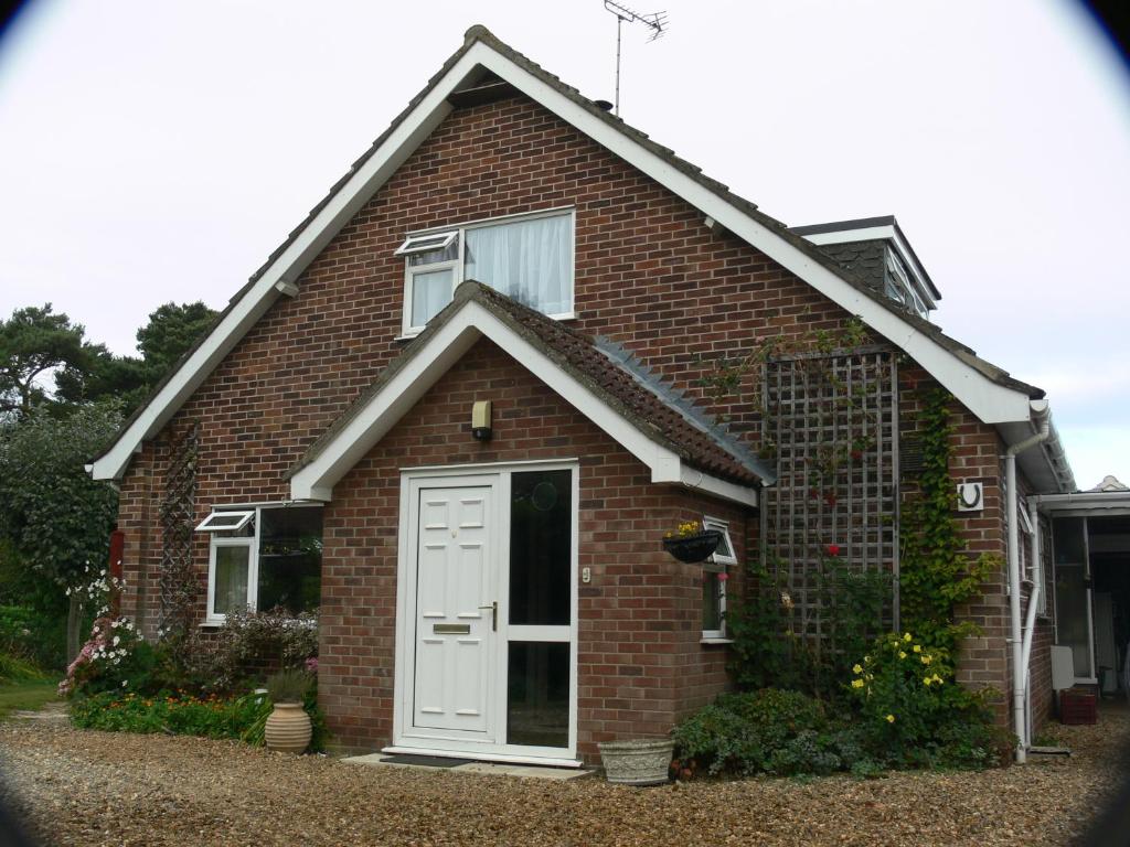 a red brick house with a white door at 3 Corners B&B in Holt