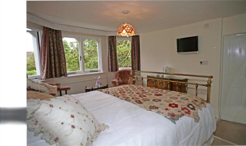 1 dormitorio con 1 cama blanca grande con lámpara de araña en West End Lodge en Esher