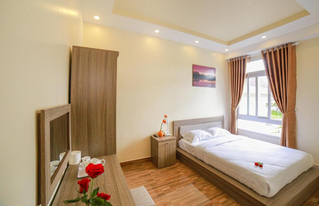 um quarto com uma cama grande e uma janela em Nhật Nguyên Hotel em Da Lat