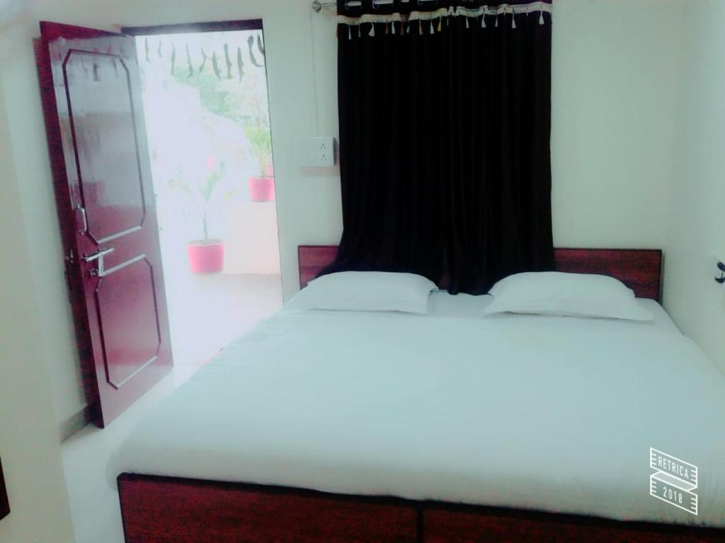 a white bed in a room with a window at Roj Cottage in Mount Ābu