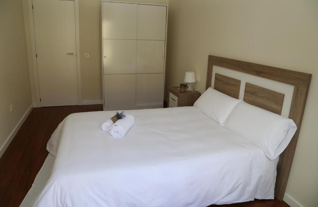 Apartamentos Turísticos Puente Romano P2 2-A في سلامنكا: غرفة نوم بسرير ابيض عليها منشفة