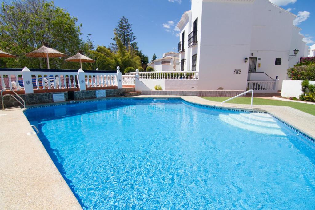a swimming pool in front of a white house at BAJAMAR II 2 MENYBER in Nerja