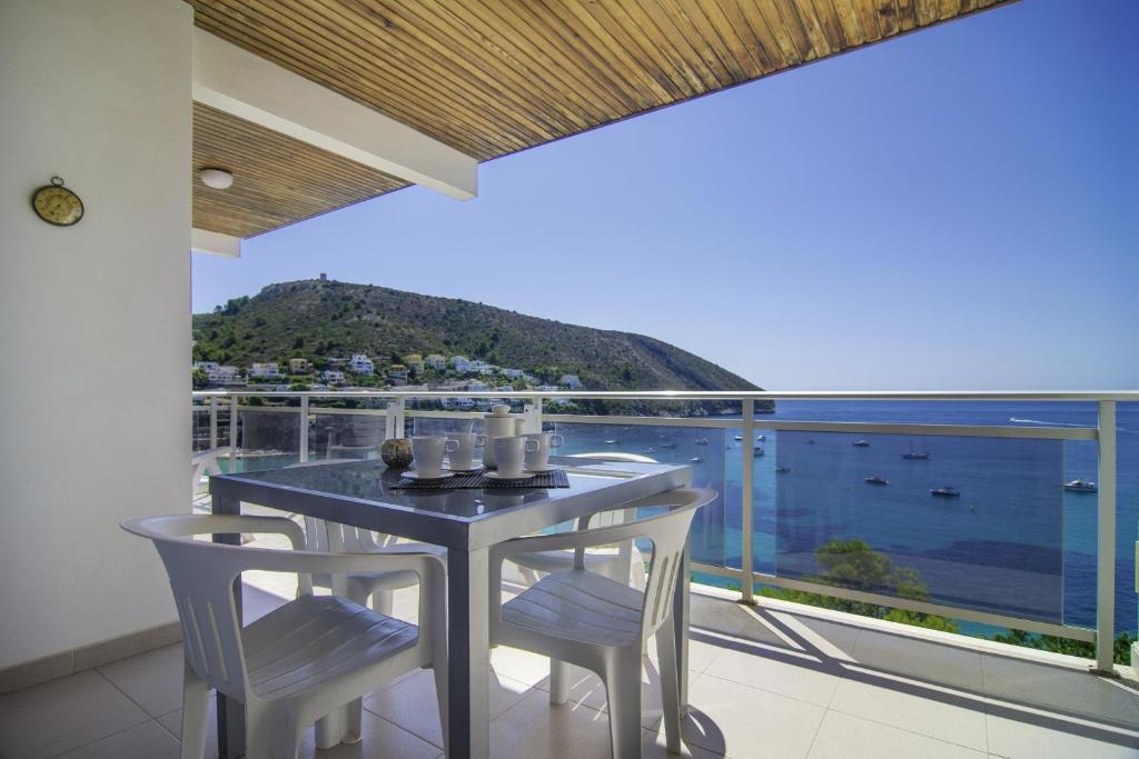 a table and chairs on a balcony with a view of the ocean at Villas Guzman - Apartamento Bellissimo in Moraira