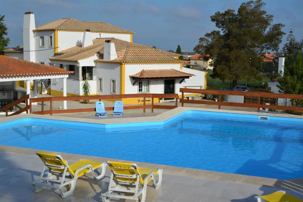 a swimming pool with chairs and a house at Casal dos Cantos in Quinta do Anjo