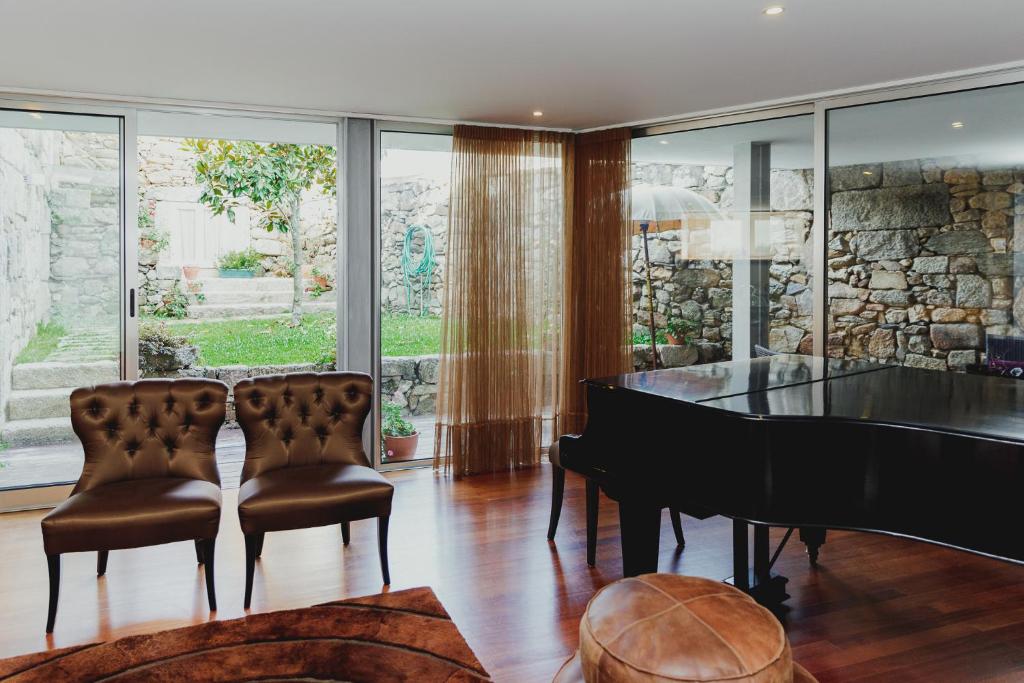 a living room with a piano and two chairs at Casa do Passadiço - Alvarenga in Alvarenga