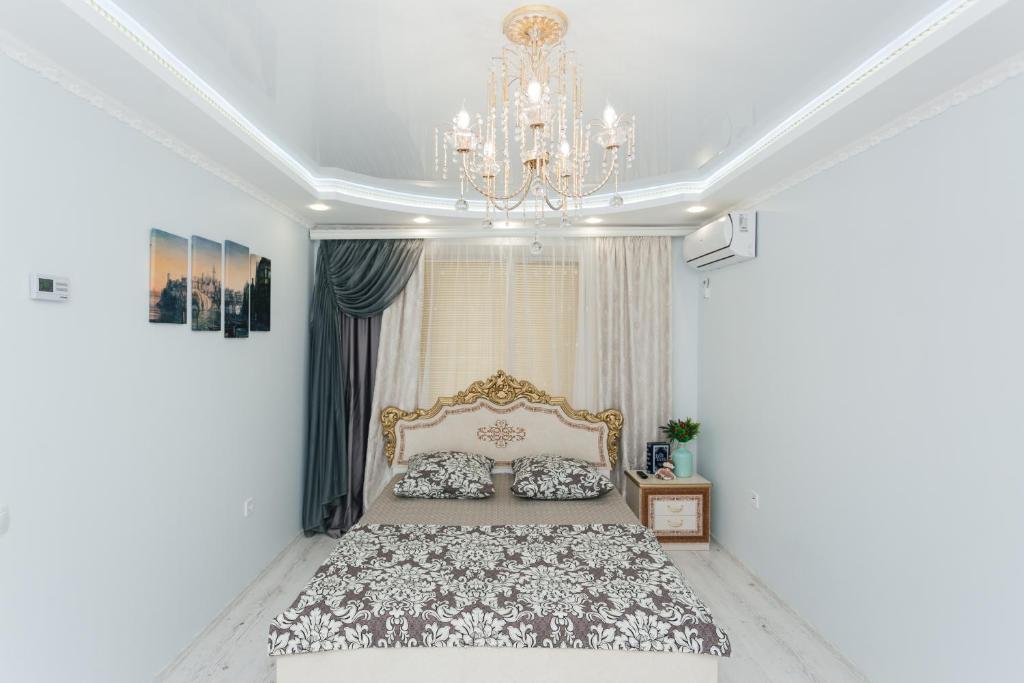 een slaapkamer met een groot bed en een kroonluchter bij De LUXE apartments Centr 1 floor in Sumy